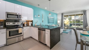 A modern kitchen with white cabinets, a black countertop island, stainless steel appliances, and pendant lighting. - Charming Villa With Private Pool Bliss (Clermont)