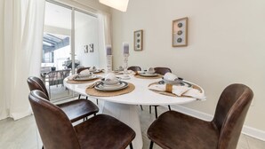 Un coin repas avec une table ronde dressée pour quatre personnes, entourée de chaises marron.