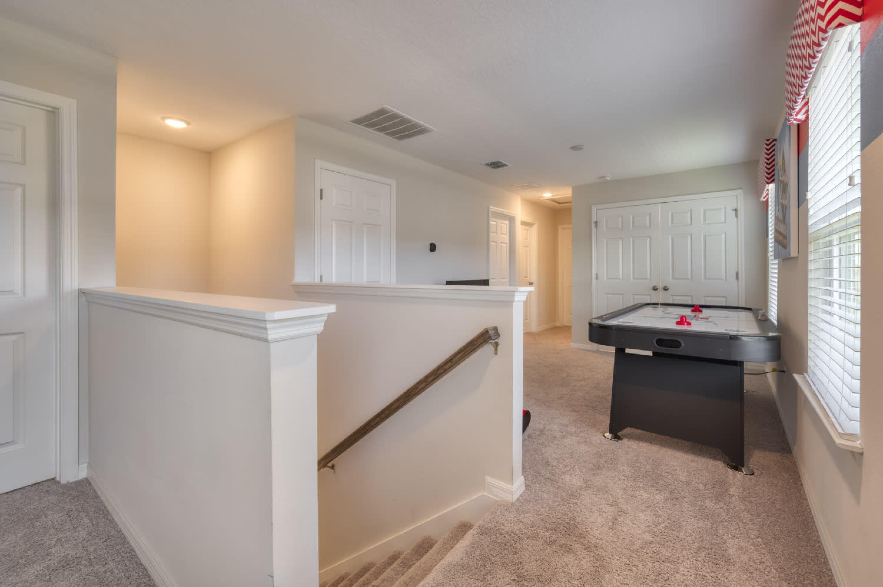 A hallway with a carpeted floor, white walls, and a pool table.