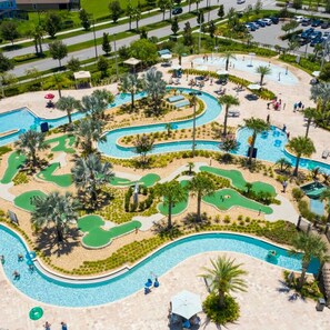 Una amplia piscina al aire libre con varias pistas, rodeada de palmeras y un campo de golf.
