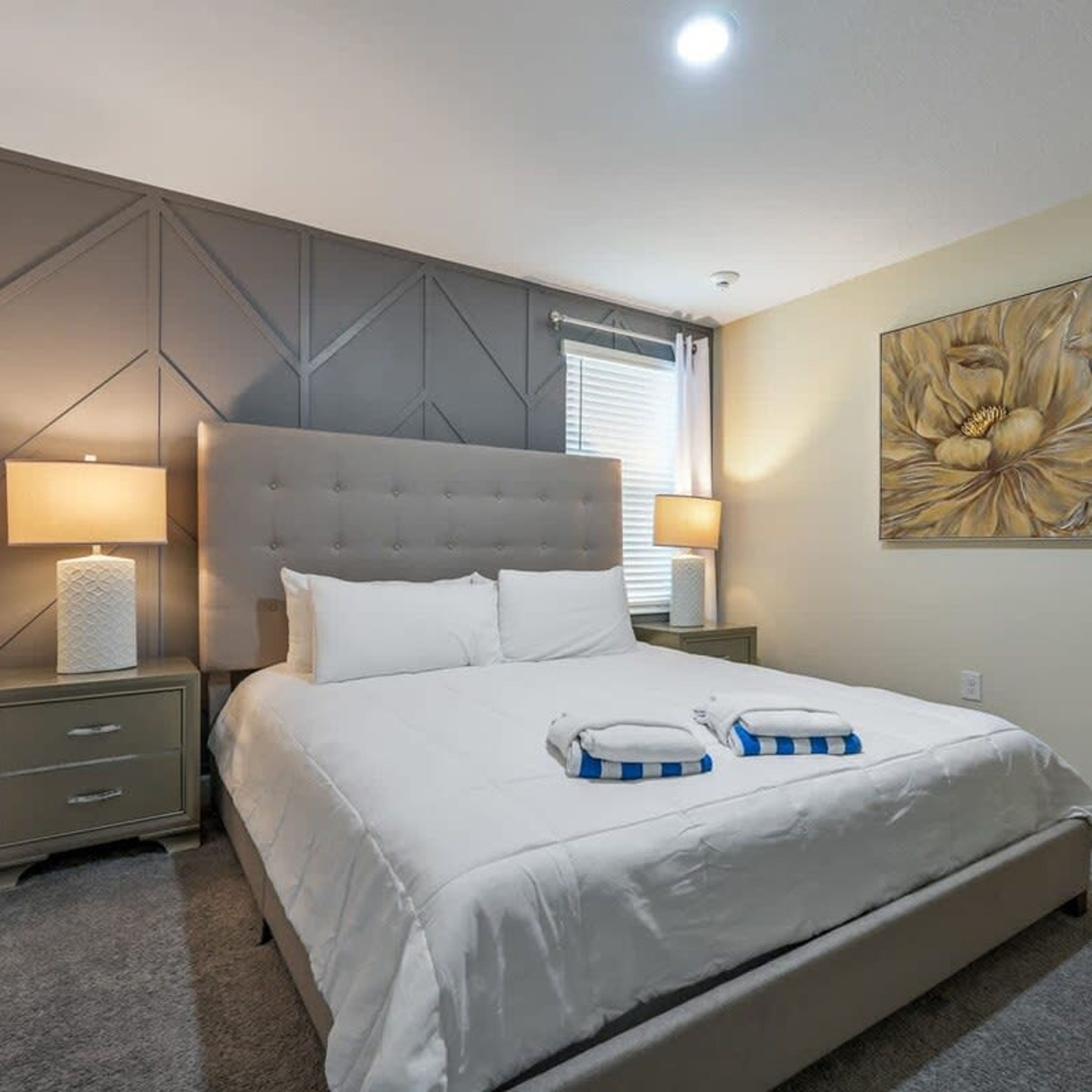 A bedroom with a large bed, two bedside tables, and a wall-mounted artwork.