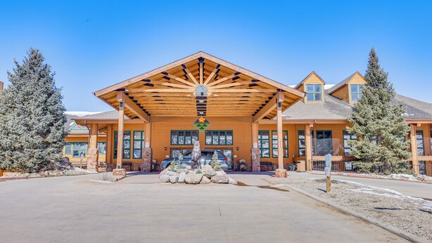 Eine Lodge mit einem großen, überdachten Eingangsbereich, Steinpfeilern und verschneiter Landschaft.