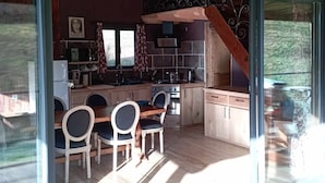 Una cocina moderna con armarios de madera, un área de comedor con mesa y sillas, y un ventanal que proporciona luz natural.