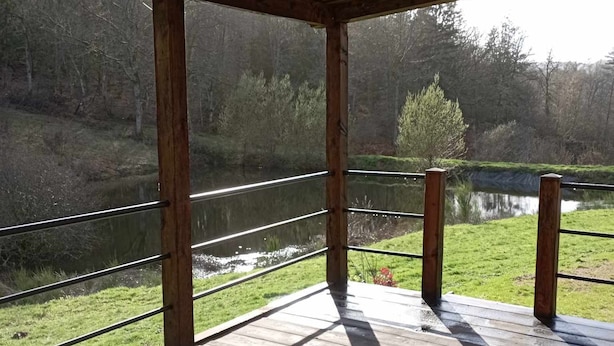 Una terraza de madera con vistas a un lago tranquilo y una zona boscosa.