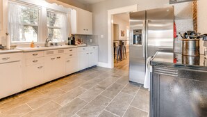 Een moderne keuken met witte kastjes, een roestvrijstalen koelkast en een betegelde vloer.