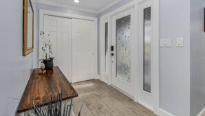 Un pasillo con un banco de madera, puertas blancas y un ventanal con vidrio satinado.