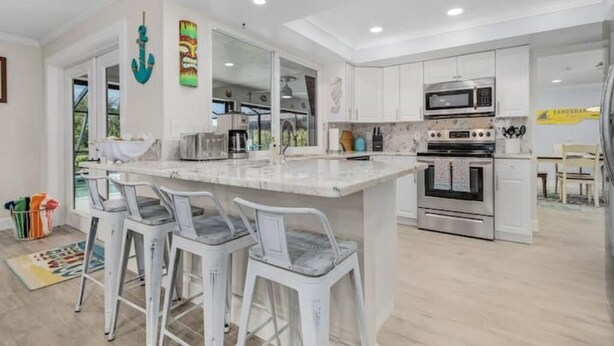 Una cocina moderna con armarios blancos, una isla de mármol y electrodomésticos de acero inoxidable.