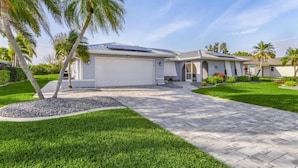 Una casa moderna de dos pisos con garaje, paneles solares y un césped bien cuidado.