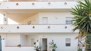 Un edificio de varios pisos con balcones, ventanas y plantas en macetas.