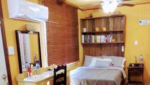 A bedroom with a bed, a desk, a chair, a bookshelf, and a ceiling fan.