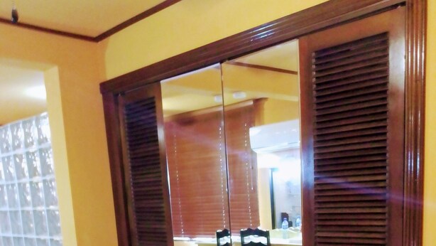 A room with a sofa, a dining table, and a kitchen area visible through a glass door.