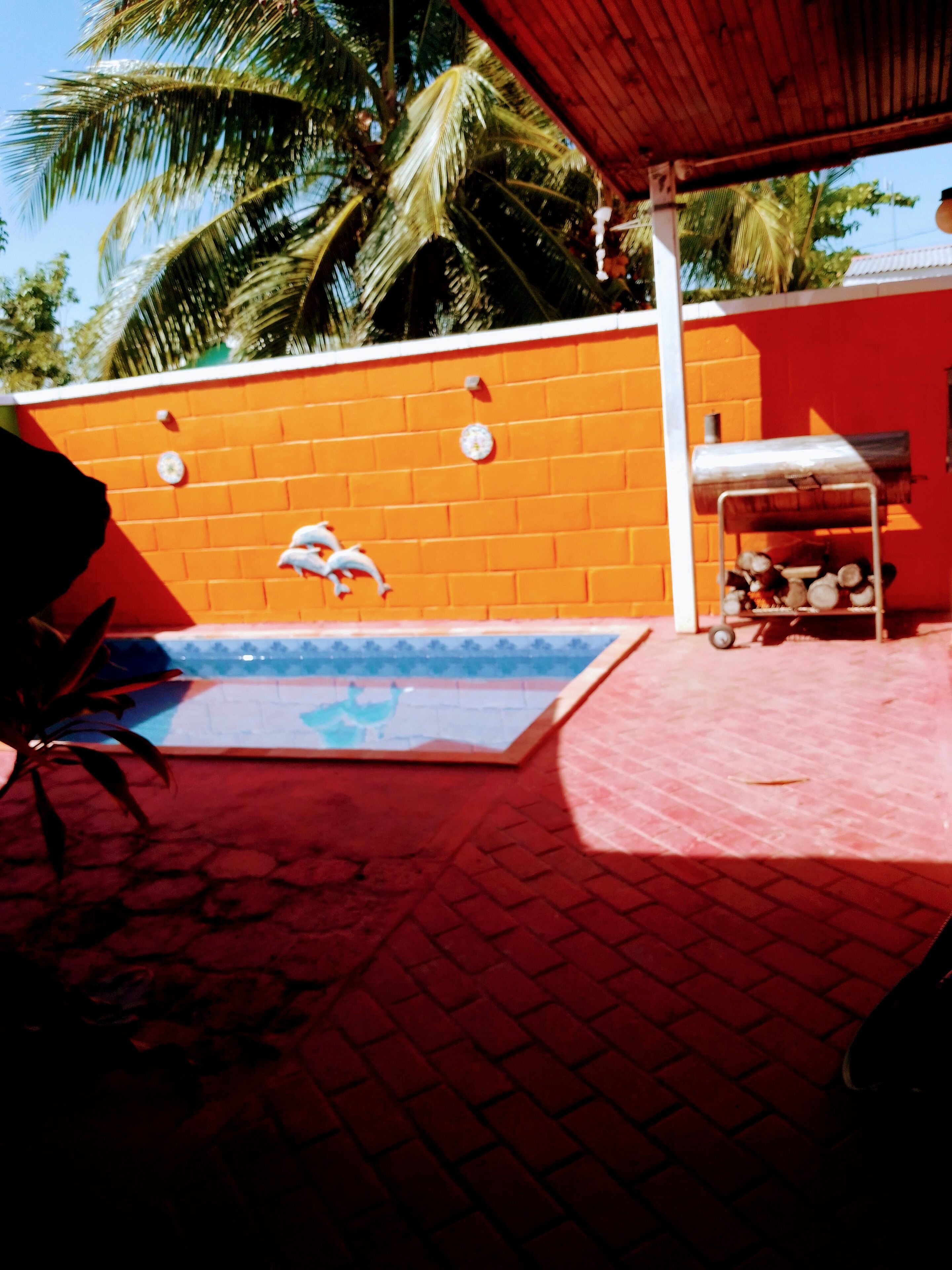 A pool area with a red brick wall, a metal grill, and a blue pool.