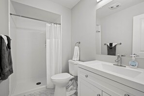 A bathroom with a shower, toilet, and sink.