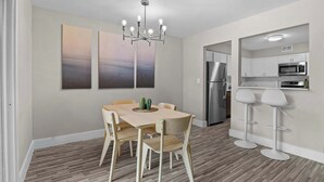Una cocina moderna con electrodomésticos de acero inoxidable, un comedor con mesa y sillas de madera, y una lámpara en el techo.