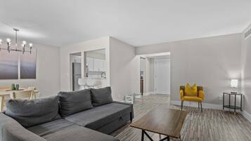 A modern living room with a grey sofa, a wooden coffee table, and a yellow armchair.