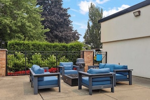 An outdoor seating area with a metal fence, a brick wall, and a white building in the background. - Stunning Stay in Rochester Hills (Rochester Hills)