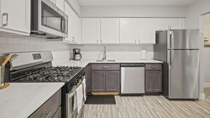 A modern kitchen with white cabinets, stainless steel appliances, and a tiled backsplash. - Modern Comfort in Rochester, Perfect Getaway (Rochester Hills)