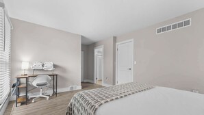 A hotel room with a bed, a desk with a chair, a lamp, and a window with blinds. - Getaway in the Heart of the City! (Rochester Hills)
