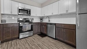 A modern kitchen with white cabinets, stainless steel appliances, and a patterned floor. - Getaway in the Heart of the City! (Rochester Hills)