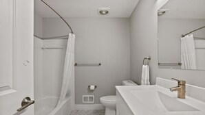 A modern bathroom with a bathtub, toilet, and sink. - Trendy & Vibrant Unit City Experience (Rochester Hills)