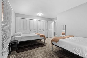 Une chambre moderne avec deux lits simples, une grande armoire et un miroir.