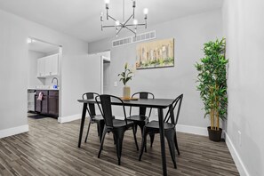 Un coin repas avec une table et des chaises, un tableau accroché au mur et une plante en pot.