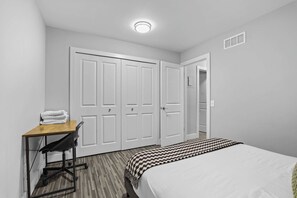 A bedroom with a bed, a desk with a chair, and a wardrobe. - Comfortable Stay near Downtown with Ammenities! (Rochester Hills)