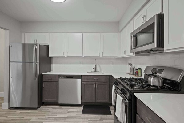 A modern kitchen with white cabinets, stainless steel appliances, and a black stove.