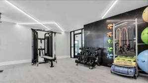 A modern gym with a pull-up bar, weight bench, and exercise balls. - Modern 2BR Retreat w/Pool & Gym | Near Downtown (Rochester Hills)