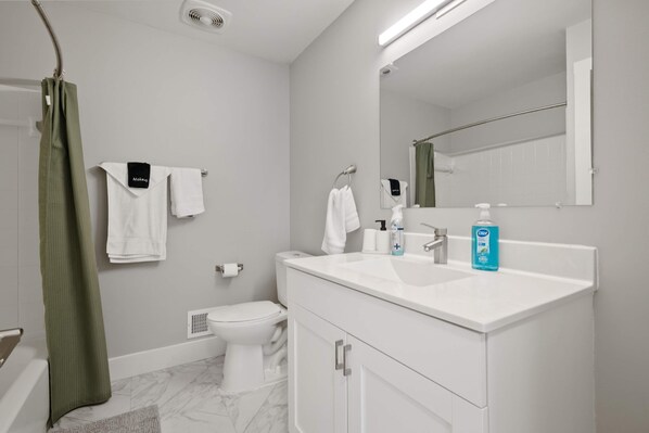 A modern bathroom with a white sink, two towel racks, a toilet, and a shower curtain.
