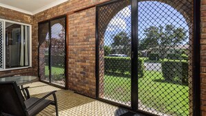A patio with a brick wall, a glass door, and a chain-link fence. - Take a dip at Eucalypt (BELLARA)