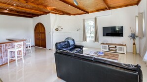 A spacious living room with a black leather sofa, a wooden coffee table, a TV mounted on the wall, and a white fireplace. - Take a dip at Eucalypt (BELLARA)