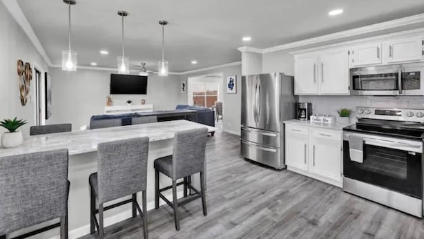 Una cocina moderna con una isla central, electrodomésticos de acero inoxidable y un televisor de pantalla plana sobre la isla.