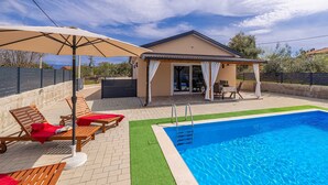 A poolside area with a covered seating area, a pool, and a building with a patio. - Holiday house ASLAN with pool (Žestilac)