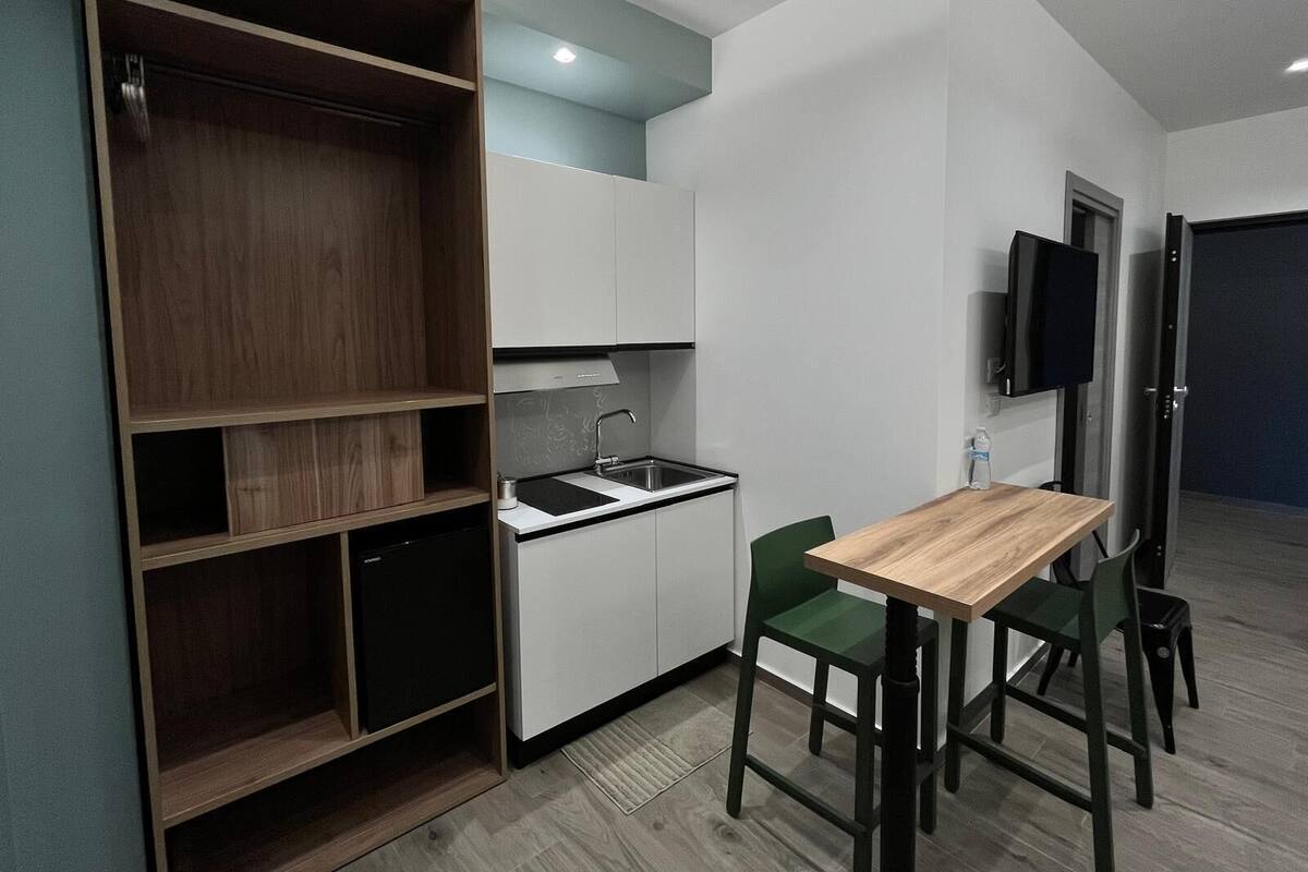 A compact kitchen with a sink, a small refrigerator, and a wooden dining table with chairs.