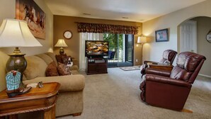 A living room with a sofa, a leather armchair, a TV, and a fireplace. - Walk-in condo with Golf Course View Near the Strip. NO STAIRS! (Branson)