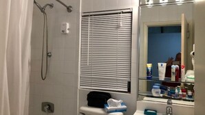 A bathroom with a shower, a toilet, a sink, and a mirror.
