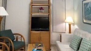 A living room with a ceiling fan, a television, a wooden cabinet, a sofa, and a lamp.
