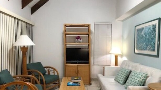 A living room with a sofa, chairs, a coffee table, a TV, and a framed picture on the wall.
