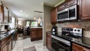 A kitchen with dark wooden cabinets, stainless steel appliances, and a central island with seating.