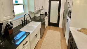 A modern kitchen with white cabinets, a black countertop, a sink, and a refrigerator.