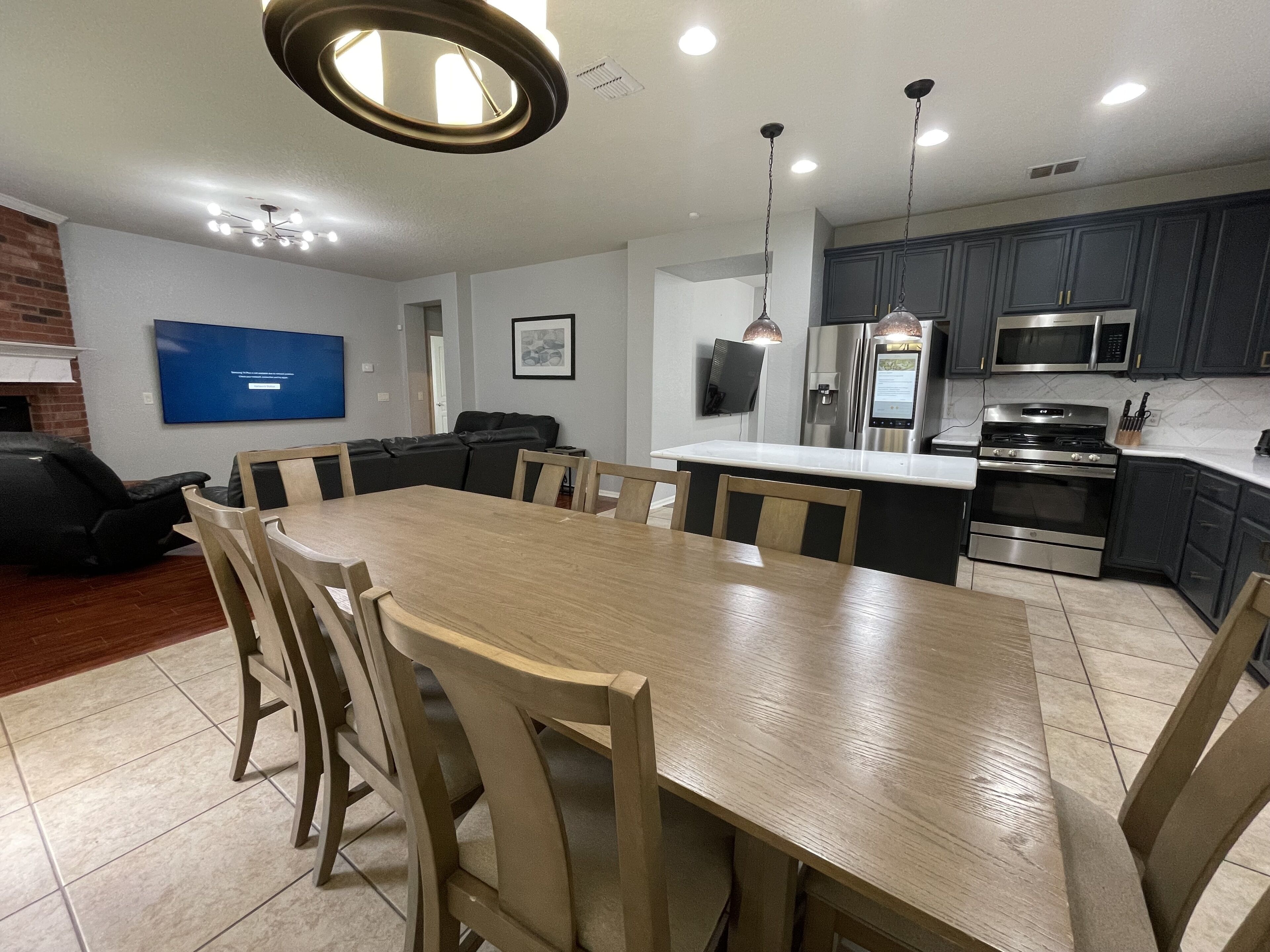 Una cocina moderna con armarios oscuros, electrodomésticos de acero inoxidable y una mesa de comedor de madera con sillas.