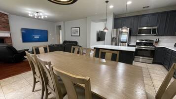 Una cocina moderna con armarios oscuros, electrodomésticos de acero inoxidable y una mesa de comedor de madera con sillas.