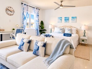 A modern bedroom with a bed, a sofa, a desk, and a ceiling fan.