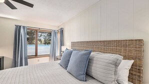 Un dormitorio con una cama grande, un cabecero de mimbre y vistas a una masa de agua a través de una ventana.