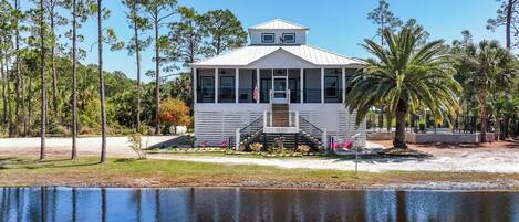A white building with a small porch, a flag, and a number '1520' on the front.
