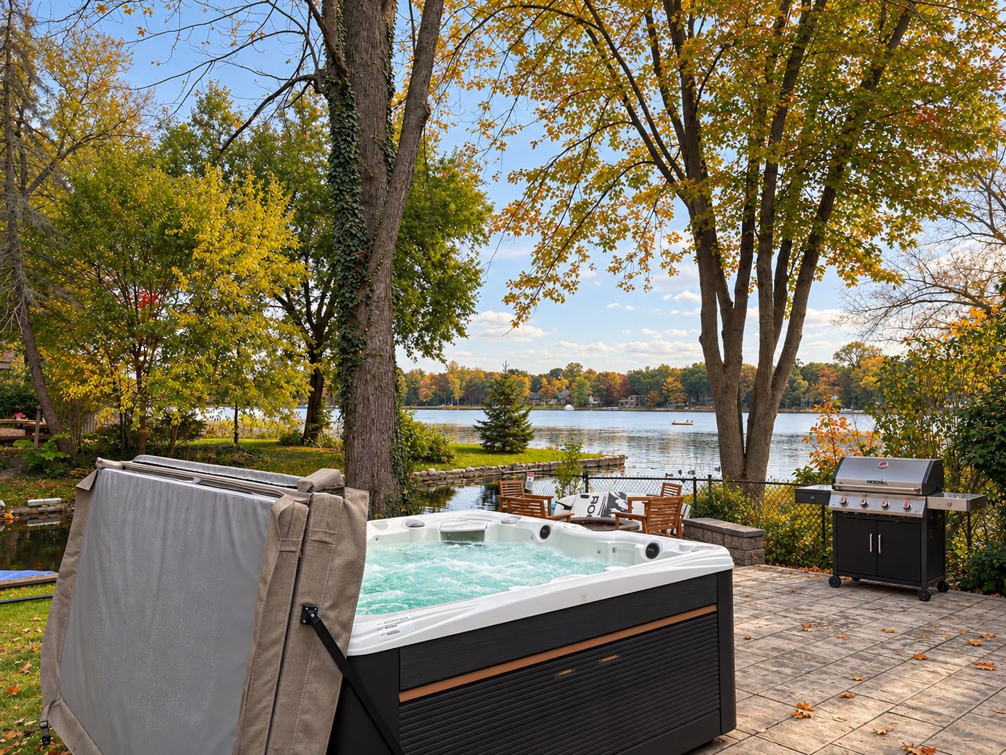 Een jacuzzi met deksel, een barbecue, en uitzicht op een meer met bomen.