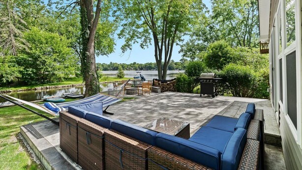 Un patio con barbacoa, mobiliario exterior y vistas a un lago.