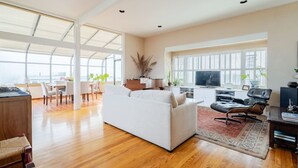 Un salón amplio con un sofá blanco, un televisor y un comedor con sillas y una mesa.