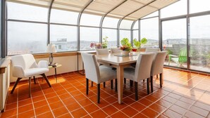 Un invernadero con una mesa de comedor, sillas y plantas en macetas.